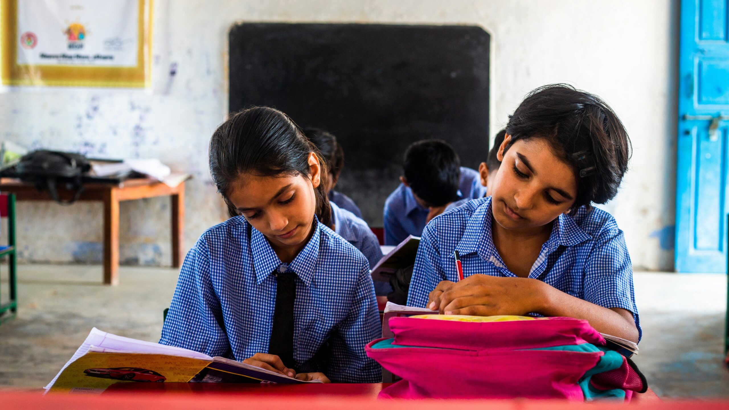 Two girls in school uniforms sitting at a desk